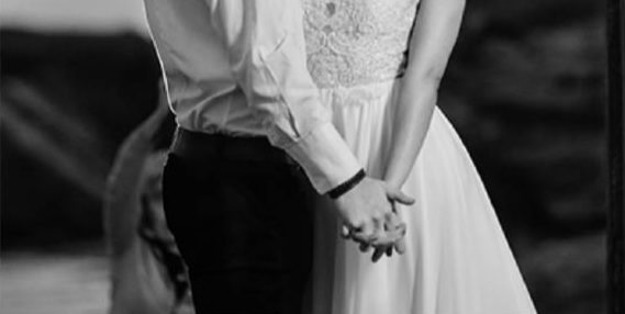 Newlyweds holding hands in black and white