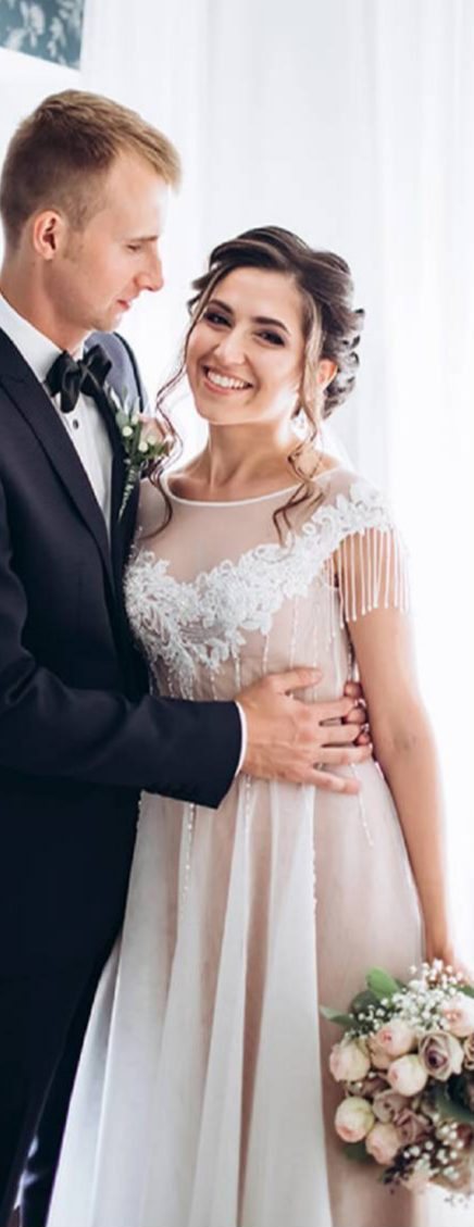 Bride and groom beside a bright tall window